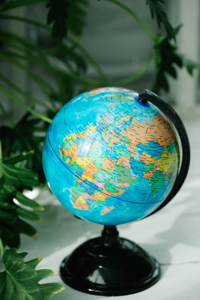 Vibrant globe on a stand surrounded by lush green plants.
